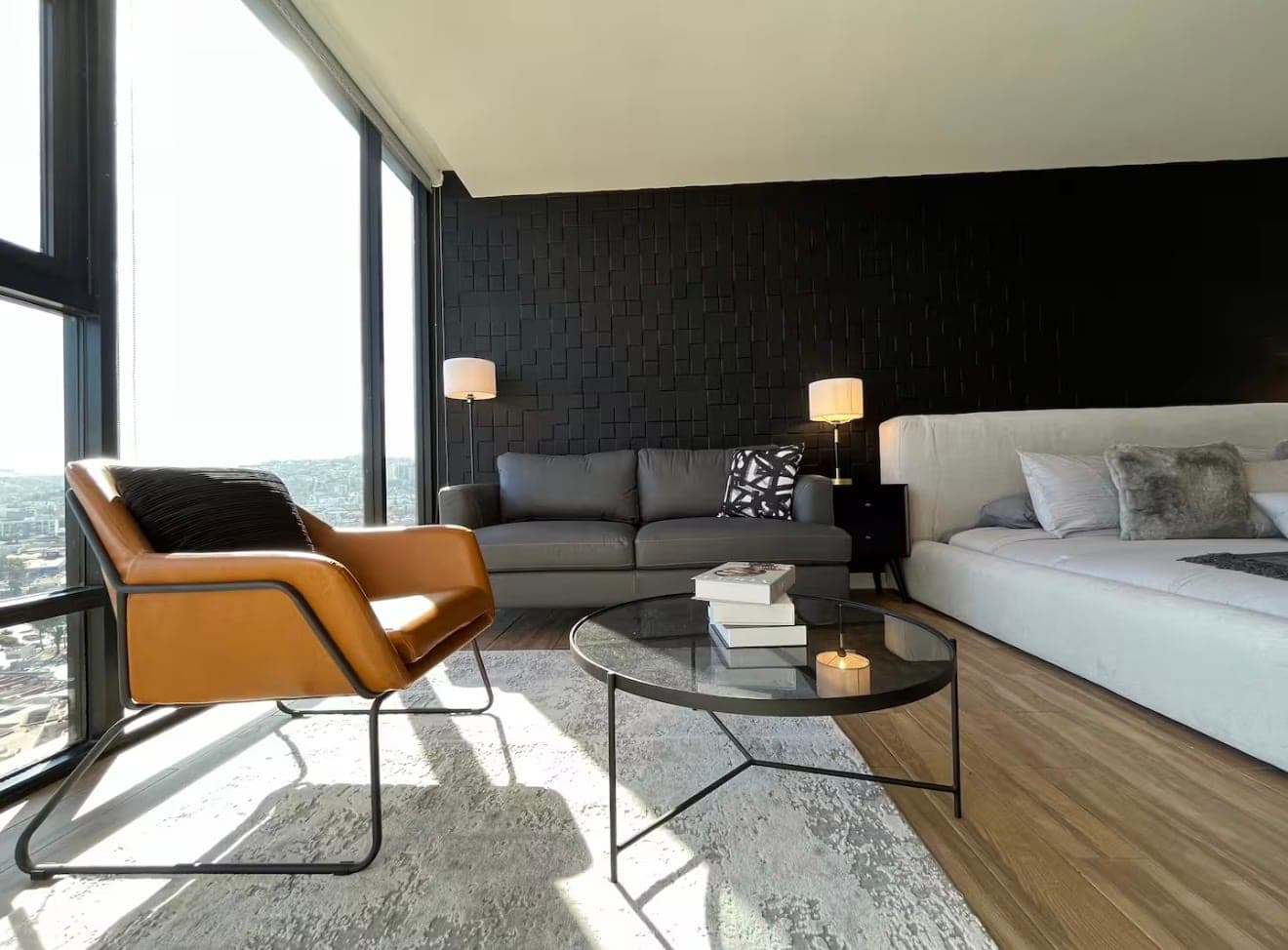 A bright living area with a leather lounge chair, a glass coffee table, and floor-to-ceiling windows